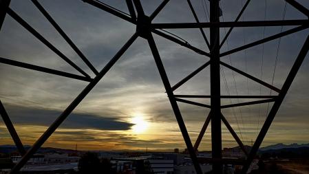 Puesta de sol en Terrassa al pie de una torre de alta tensión.