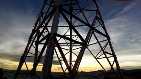Puesta de sol en Terrassa al pie de una torre de alta tensión.
