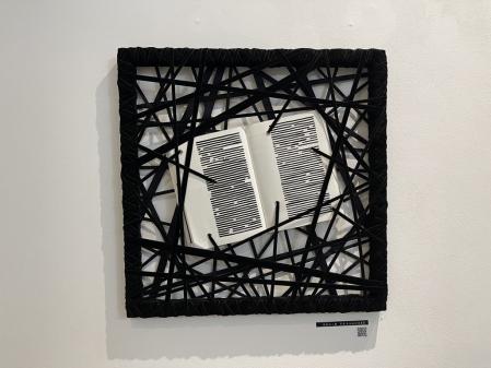 Obra de Genís Fernández Benítez: N. 10 Censored  art book. 49,5 X 49,5 cm. Marco de madera, libro de arte censurado y cintas negras de terciopelo, hechas con materia reciclado.