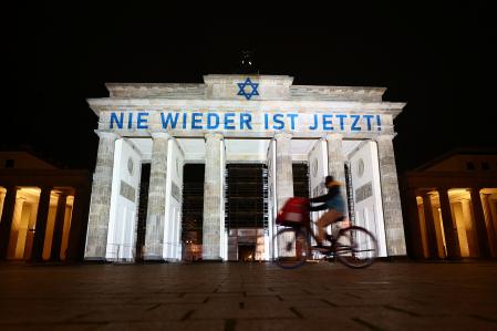 A person rides a bike past the Brandenburg Gate illuminated in the colours of Israel and the Star of David, in Berlin, Germany November 9, 2023. The message is reading 