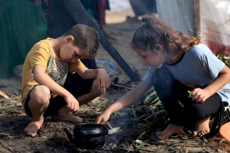 Internally displaced Palestinian children, who fled from the Israeli bombardment of the northern Gaza Strip and are now living in make shift shelters, light a fire to boil a kettle after overnight rainstorms in Khan Yunis, in the southern Gaza Strip on November 15 , 2023, amid the ongoing battles between Israel and the Palestinian group Hamas. The war between Israel and Hamas has displaced almost 1.6 million Palestinians, according UNRWA, leaving hundreds of thousands living in cramped shelters with little food and insufficient water. More than 11,000 people have been killed in relentless Israeli bombardment of the Gaza Strip, according to the Hamas-run health ministry, since the war erupted after Palestinian militants raided southern Israel on October 7 killing at least 1200 people, according to official Israeli figures. (Photo by MAHMUD HAMS / AFP)