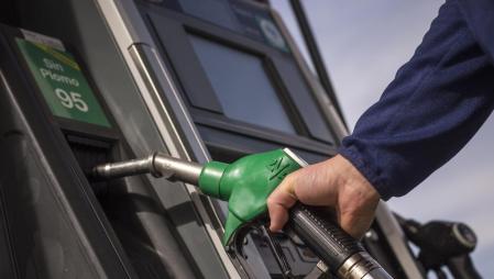 Un usuario sostiene la manguera de un surtidor de gasolina sin plomo 95&nbsp;