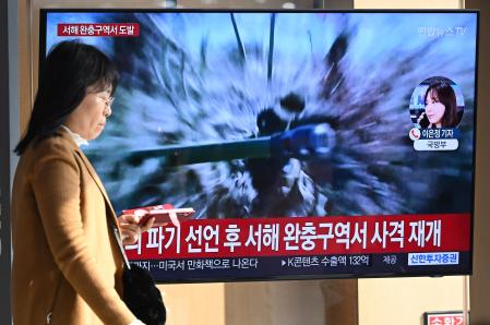 TOPSHOT - A woman walks past a television screen showing a news broadcast with file footage of North Korea's artillery firing, at a railway station in Seoul on January 5, 2024. North Korea fired more than 200 artillery shells near two South Korean islands on January 5, Seoul's defence ministry said, with an evacuation order issued for residents on one of them. (Photo by Jung Yeon-je / AFP)