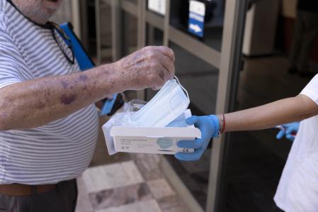 SANTA CRUZ DE TENERIFE (ESPAÑA), 09/01/2024.- Este miércoles ha entrado en vigor la orden del Gobierno de Canarias que obliga a utilizar mascarilla en todos los centros sanitarios de la comunidad autónoma, ante el gran número de contagios de gripe y covid. En la imagen, una trabajadora de un centro de salud de Santa Cruz de Tenerife entrega una mascarilla a un paciente. EFE/Miguel Barreto