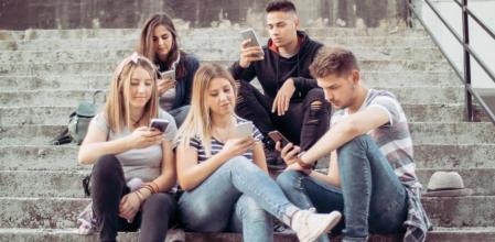 Jóvenes mirando el teléfono en unas escaleras