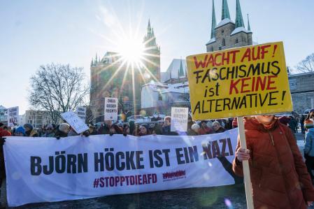 A woman holds a placard reading 
