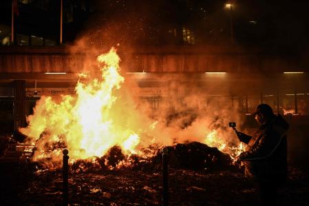 Un hombre toma imágenes de fardos de heno quemados durante una protesta de los agricultores frente a la prefectura de Gironda, en Burdeos.