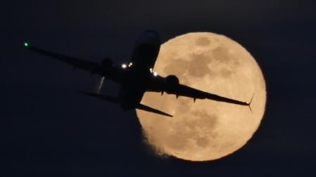 El avión y la luna llena del lobo, visto desde la playa de Gavà.