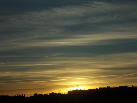 El sol asoma entre las estelas en Madrid.