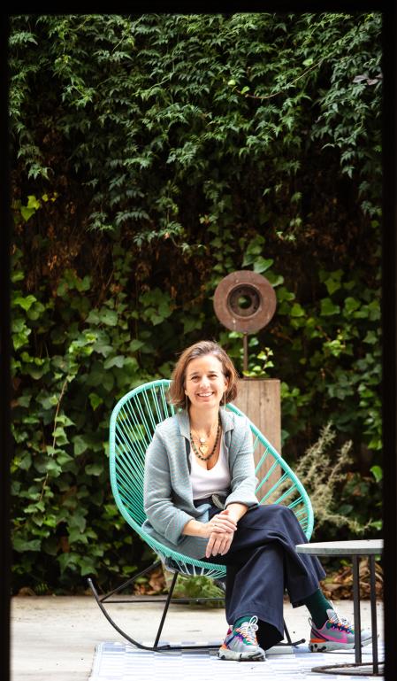 En el patio, Bárbara Aurell sentada en la silla Acapulco, detrás, escultura de Nuria Arfa