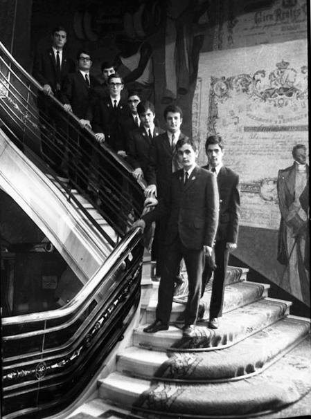 Botones del Banco de Bilbao en 1965 posando en las escaleras de la oficina principal de Barcelona. En la parte aparece dibujado un “reales de vellón”.