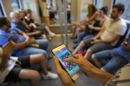Una mujer jugando a un videojuego móvil en el transporte público&nbsp;