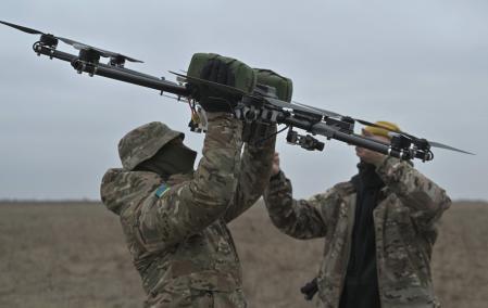Pilots carry a drone on a training ground in Kyiv region on February 23, 2024, amid the Russian invasion of Ukraine. (Photo by Genya SAVILOV / AFP)
