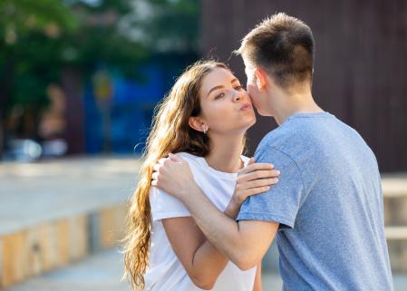 Young man and girl are hugging and kissing each other in cheek
