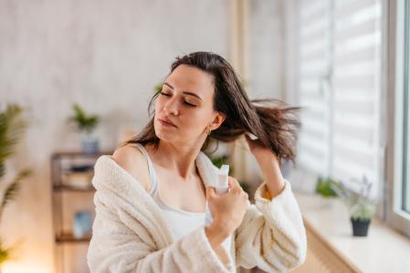 Una mujer aplicándose producto en el cabello.
