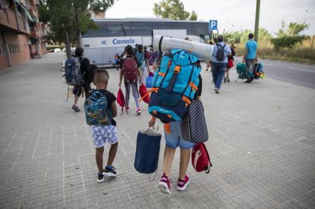 Padres que cargan con las mochilas de sus hijos, que parten de colonias en Cornellà