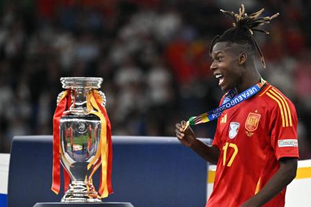 Spain's midfielder #17 Nico Williams celebrates with his silver medal next to the trophy after winning the UEFA Euro 2024 final football match between Spain and England at the Olympiastadion in Berlin on July 14, 2024. (Photo by JAVIER SORIANO / AFP)