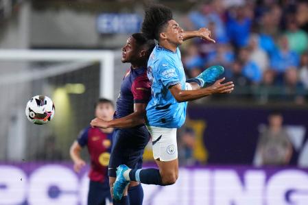 ORLANDO, FLORIDA - JULY 30: Vitor Roque #17 of FC Barcelona and Rico Lewis #82 of Manchester City compete for a header in the first half of a pre-season match between Manchester City and FC Barcelona at Camping World Stadium on July 30, 2024 in Orlando, Florida. Rich Storry/Getty Images/AFP (Photo by Rich Storry / GETTY IMAGES NORTH AMERICA / Getty Images via AFP)