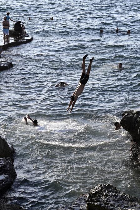 Beirut (Lebanon), 03/09/2024.- A youth jumps into the Mediterranean Sea while others watch, during a sunny day at the Corniche Al Manara in Beirut, Lebanon, 03 September 2024. (Líbano) EFE/EPA/WAEL HAMZEH