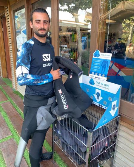 Un submarinista deposita un traje en uno de los contenedores que se han instalado en los centros participantes de la iniciativa.