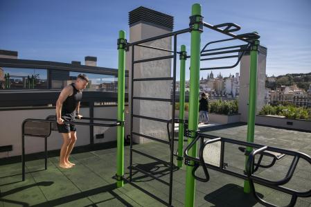 Un residente practica calistenia en la estación funcional instalada en la terraza de la comunidad