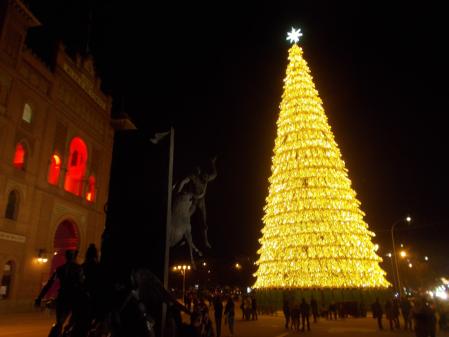 Árbol de Navidad gigante  de la plaza de Las Ventas, el segundo más alto tras el de Sol,  con el Yiyo en primer término y la plaza de toros a la izquierda iluminada de rojo.