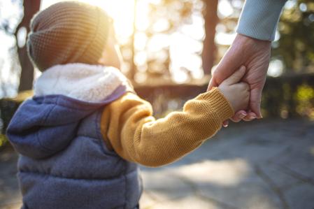 Close up of mother and a child hands at the sunset. A parent holds the hand of a small boy in the sunset. Mother holding her little boys hand walking down the street
