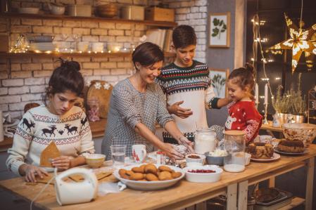 Mother with children in kitchen preparing Christmas cakes