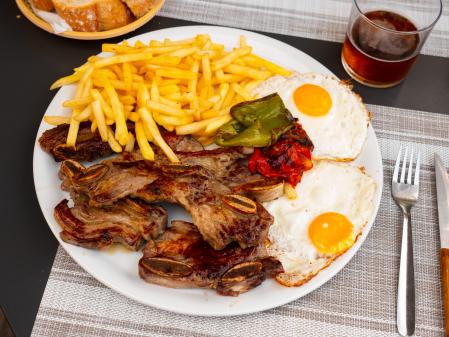 Un plato combinado con churrasco, pimiento, huevos y patatas fritas