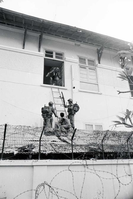 Soldados survietnamitas acceden con una escala a una parte de la embajada estadounidense en Saigón en busca de guerrilleros del Vietcong