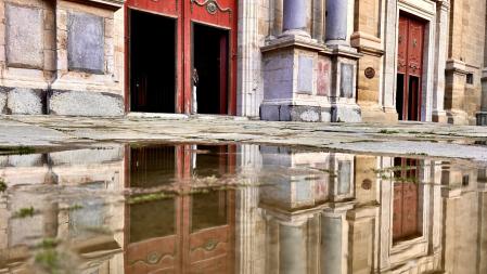 La entrada de la catedral de Vic reflejada en un charco.