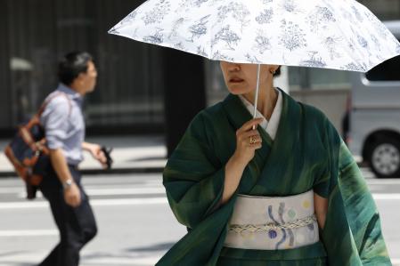 Una mujer ataviada con un kimono se cubre con una sombrilla.