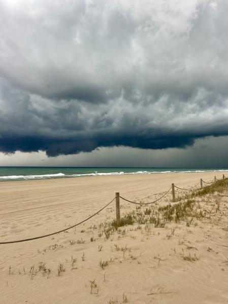 La playa de Gavà Mar desalojada tras la alerta de la dana, con las amenazadoras nubes de la tormenta.