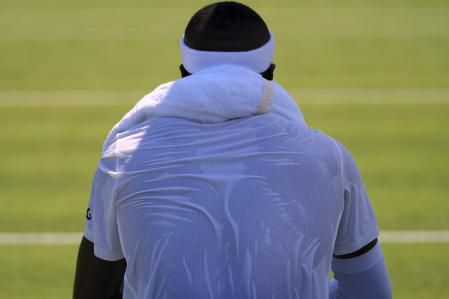 Frances Tiafoe, tenista estadounidense, con la camiseta empapada por el sudor y una toalla húmeda sobre el cuello, en Wimbledon 2025