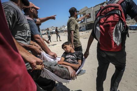 Palestinos llevan el cuerpo de un niño después de que fuera asesinado a tiros en un punto de distribución de alimentos cerca de Zikim,