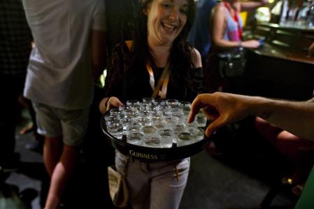 Una empleada de un bar reparte chupitos entre los asistentes a una ruta de borrachera