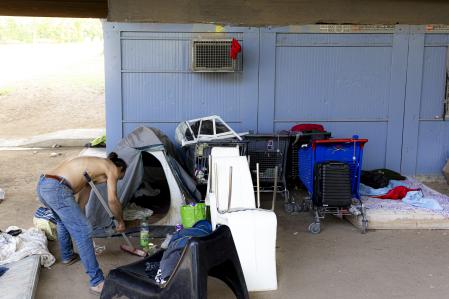 Un hombre barre entre tiendas de campaña, carritos del súper y sillas