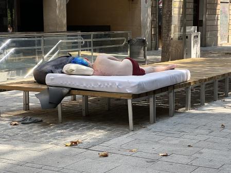 Un turista durmiendo en Consell de Cent por la mañana.