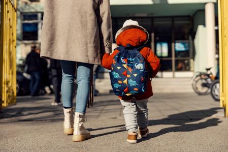Un niño con mochila entrando al colegio.