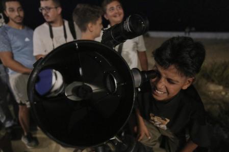 Gente viendo el eclipse lunar por un telescopio.
