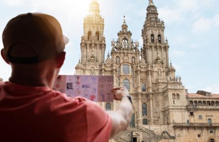 Un peregrino revisa su credencial frente a la catedral de Santiago