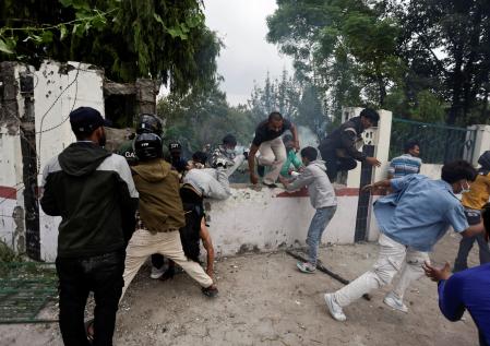 Alborotadores saltan el muro del recinto del Parlamento, perseguidos por los policía antidisturbios.&nbsp;
