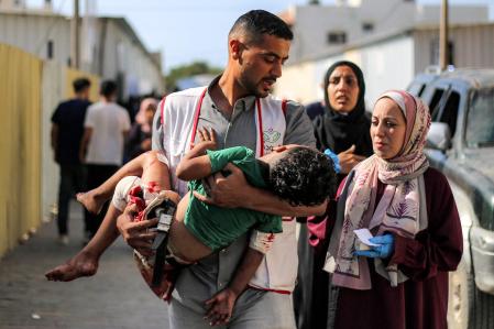 Un médico del hospital al-Awda lleva en brazos a un niño gravemente herido por un bombardeo israelí sobre el barrio en al-Bureij en Gaza