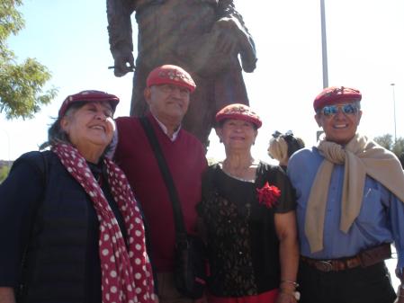 Un grupo de aficionados ataviados con gorras e insignias posan junto al monumento.