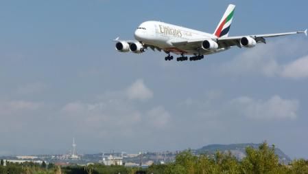 El icono de la aviación , el A380 de Emirates, sobrevolando símbolos de Montjuïc con el Estadi, el Palau Sant Jordi y la Torre Calatrava, en su aproximación al aeropuerto de El Prat, visto desde El Mirador de los Aviones.
