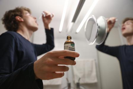 Joven consumiendo melatonina en gotas, suplemento para ayudar a dormir.