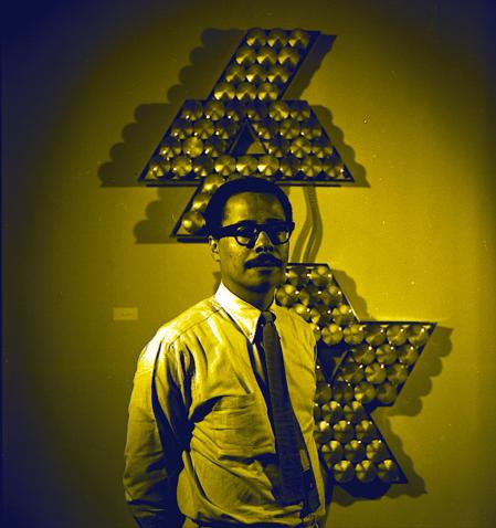 Retrato de Tom Lloyd, el primer artista que expuso en el Studio Museum, en 1968, delante de una de sus obras