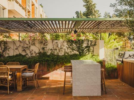 La terraza, con pérgola metálica con lamas de madera, cuenta con una cocina exterior