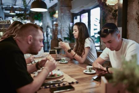 Jóvenes mirando el móvil en una cafetería.