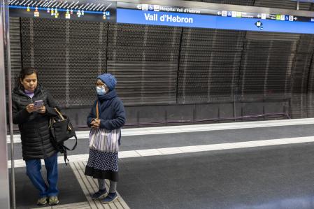 Dos mujeres, una protegida con una mascarilla, ante la entrada de la línea 5 del Metro de Barcelona en la parada de Vall d'Hebron, cerca del hospital.&nbsp;